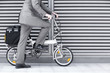 Photo: Businessman cycling on folding commuter bicycle on pavement, side view, low section Businessman cycling on folding commuter bicycle on pavement, side view, low section