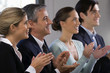 Side profile of four business executives clapping in a row and smiling