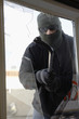 Masked thief braking glass with crowbar