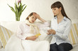 Photo: Mid adult woman suffering from fever with her friend reading a medicine bill beside her Mid adult woman suffering from fever with her friend reading a medicine bill beside her