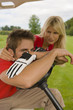 Photo: Side profile of a mid adult man sitting in a golf cart with a mid adult woman standing beside him Side profile of a mid adult man sitting in a golf cart with a mid adult woman standing beside him