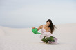 A woman watering a plant in the sand