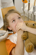 Close-up of a girl with her hands over her mouth in a dentist's office