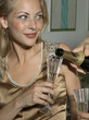 Photo: Close-up of a person's hand pouring champagne into a champagne flute held by a young woman Close-up of a person's hand pouring champagne into a champagne flute held by a young woman