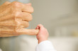 A baby's hand holding their grandparent's finger