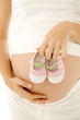 A pregnant woman holding a pair of baby shoes