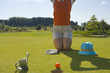 Mid section view of a mid adult woman kneeling on grass on a golf course