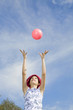 Girl throwing pink ball in air