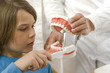Dental assistant teaching a boy how to brush teeth
