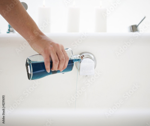 Photo: Pouring bath oil in a bath Pouring bath oil in a bath