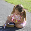 Young girl writing in chalk on the playground