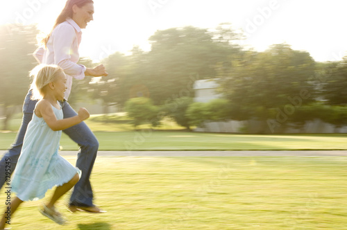 Photo: A mother and her young daughter running in a park A mother and her young daughter running in a park