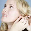 A young woman putting on earrings