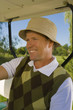 Close-up of a mid adult man sitting in a golf cart and smiling