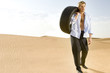 A man standing in the desert with a tyre