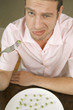 Young man making face and eating peas