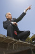 Photo: Low angle view of a businessman crouching on a boardwalk and pointing with his finger Low angle view of a businessman crouching on a boardwalk and pointing with his finger