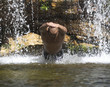 Young man diving into a natural pool near a waterfall