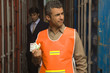 Photo: Close-up of a dock worker holding currency notes with a businessman in the background Close-up of a dock worker holding currency notes with a businessman in the background
