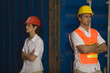 Two dock workers leaning against a cargo container
