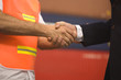 Mid section view of a businessman shaking hands with a male dock worker
