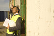 Photo: Side profile of a businessman leaning against a cargo container and looking tired Side profile of a businessman leaning against a cargo container and looking tired