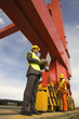 Photo: Low angle view of a businessman using a laptop with a male dock worker working at a commercial dock Low angle view of a businessman using a laptop with a male dock worker working at a commercial dock