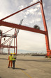 Businessman using a laptop with a male dock worker at a commercial dock