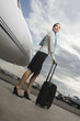 Photo: Side profile of a cabin crew standing and holding her luggage near a private airplane Side profile of a cabin crew standing and holding her luggage near a private airplane