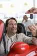 Photo: Salesman handing key to satisfied male customer sitting in red convertible in car showroom, smiling Salesman handing key to satisfied male customer sitting in red convertible in car showroom, smiling