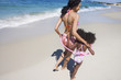 Photo: Mother and daughter (6-8) walking along sandy beach near water's edge, arms around each other, rear view Mother and daughter (6-8) walking along sandy beach near water's edge, arms around each other, rear view