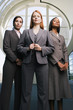 Photo: Three confident businesswomen, in grey suits, standing in lobby, front view, portrait Three confident businesswomen, in grey suits, standing in lobby, front view, portrait