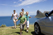 Foto: Family running towards parked car on clifftop overlooking Atlantic Ocean, smiling, portrait Family running towards parked car on clifftop overlooking Atlantic Ocean, smiling, portrait