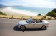 Photo: South Africa, Cape Town, family man driving silver convertible car along coastal road, side view South Africa, Cape Town, family man driving silver convertible car along coastal road, side view
