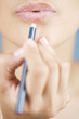A young woman applying lip liner
