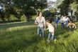 Photo: Multi-generational family playing with soccer ball in woodland clearing, mother and daughter (8-10) running away Multi-generational family playing with soccer ball in woodland clearing, mother and daughter (8-10) running away