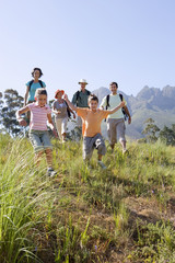 Photo: Multi-generational family hiking on mountain trail, boy and girl (8-10) leading, front view Multi-generational family hiking on mountain trail, boy and girl (8-10) leading, front view