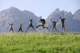 Photo: Multi-generational family hiking on mountain trail, jumping in line, arms up, front view, portrait Multi-generational family hiking on mountain trail, jumping in line, arms up, front view, portrait