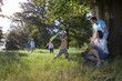 Photo: Multi-generational family exploring woodland clearing, parents resting beside tree, boy (8-10) playing with kite Multi-generational family exploring woodland clearing, parents resting beside tree, boy (8-10) playing with kite