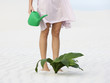 A woman watering a plant in the sand