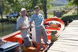 Photo: Grandfather and grandson (8-10) standing in motorboat beside lake jetty, boy tying rope to mooring post, portrait Grandfather and grandson (8-10) standing in motorboat beside lake jetty, boy tying rope to mooring post, portrait