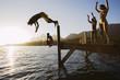 Photo: Father and son (8-10), in swimwear, diving off jetty into lake at sunset, mother and daughter (7-9) cheering (lens flare) Father and son (8-10), in swimwear, diving off jetty into lake at sunset, mother and daughter (7-9) cheering (lens flare)