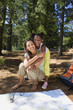 Photo: Mother and daughter (7-9) resting on lakeside woodland trail beside map and compass, girl embracing woman, smiling, portrait Mother and daughter (7-9) resting on lakeside woodland trail beside map and compass, girl embracing woman, smiling, portrait
