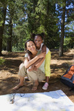 Photo: Mother and daughter (7-9) resting on lakeside woodland trail beside map and compass, girl embracing woman, smiling, portrait Mother and daughter (7-9) resting on lakeside woodland trail beside map and compass, girl embracing woman, smiling, portrait