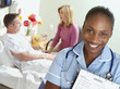 Photo: Male patient lying in hospital bed, talking to visitor, focus on nurse in foreground, smiling, portrait Male patient lying in hospital bed, talking to visitor, focus on nurse in foreground, smiling, portrait