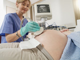 Photo: Pregnant woman having ultrasound scan performed by female doctor in hospital, side view Pregnant woman having ultrasound scan performed by female doctor in hospital, side view