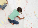 Photo: Boy and girl (7-10) drawing on large piece of paper laid out on living room floor, overhead view Boy and girl (7-10) drawing on large piece of paper laid out on living room floor, overhead view