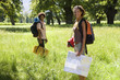 Photo: Young couple, with rucksacks, standing in woodland clearing, departing on hiking trip, woman holding map, smiling, portrait Young couple, with rucksacks, standing in woodland clearing, departing on hiking trip, woman holding map, smiling, portrait