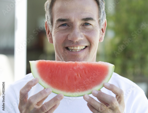 Photo: A man holding a slice of watermelon A man holding a slice of watermelon