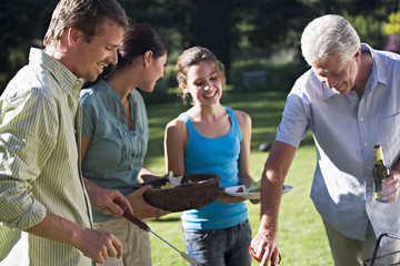 Photo: Three generation family having barbecue in summer garden, men serving food from grill, girl (11-13) holding plate, woman with salad bowl, smiling Three generation family having barbecue in summer garden, men serving food from grill, girl (11-13) holding plate, woman with salad bowl, smiling